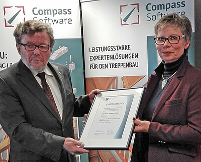 [Translate to Amerikanisch:] Anlässlich des 25-jährigen Bestehens von Compass Software überreichte Frau Preiß von der IHK eine Ehrenurkunde als Anerkennung zum Firmenjubiläum an unseren Geschäftsführer Detlef Hollinderbäumer. 